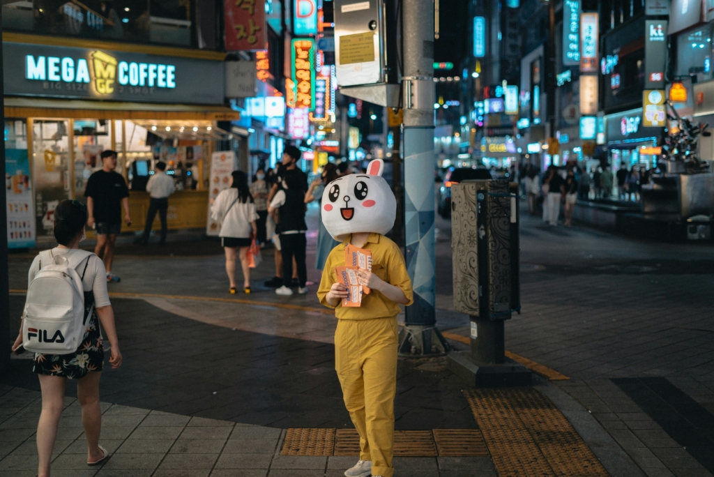 une mascotte de marque distribue des flyers dans la rue