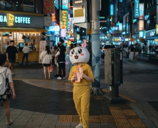 une mascotte de marque distribue des flyers dans la rue