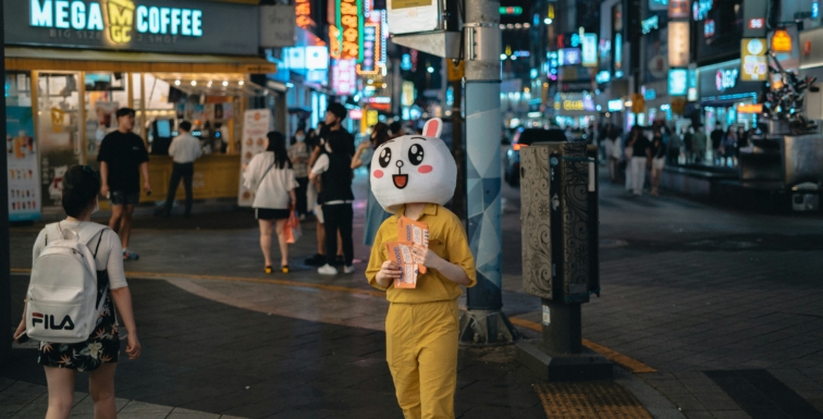 une mascotte de marque distribue des flyers dans la rue